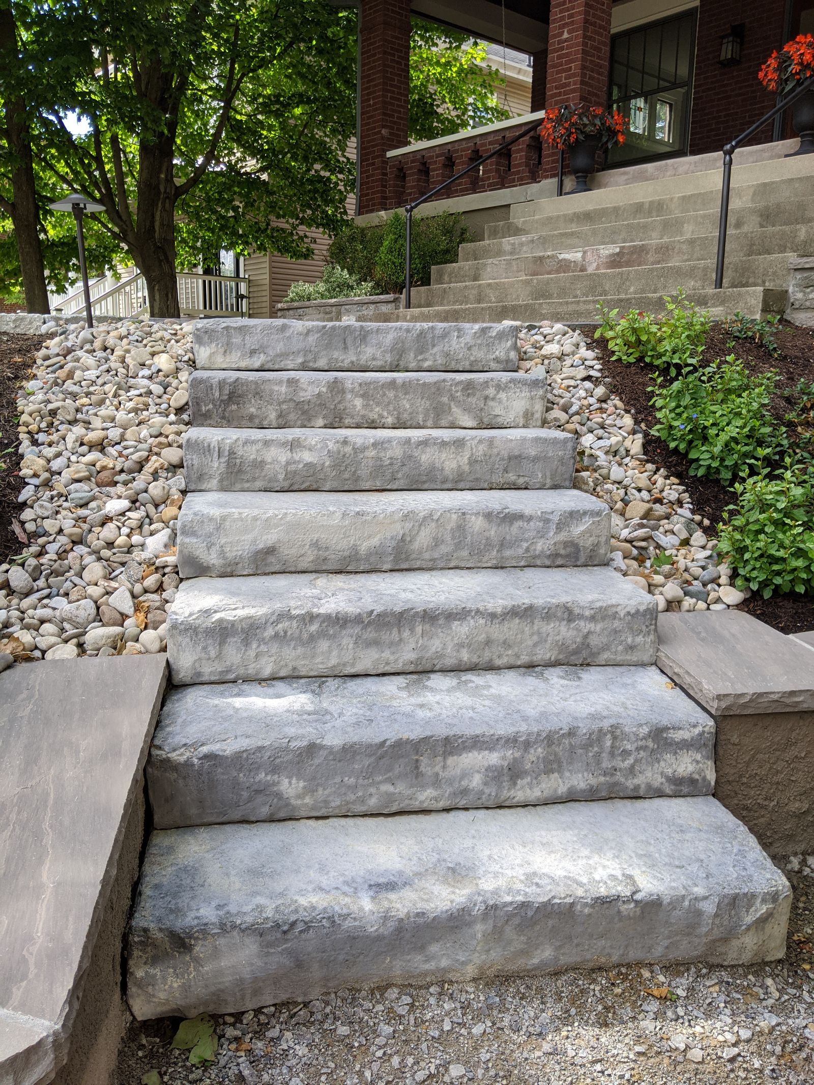 Natural stone steps with steel railings beside the brick home