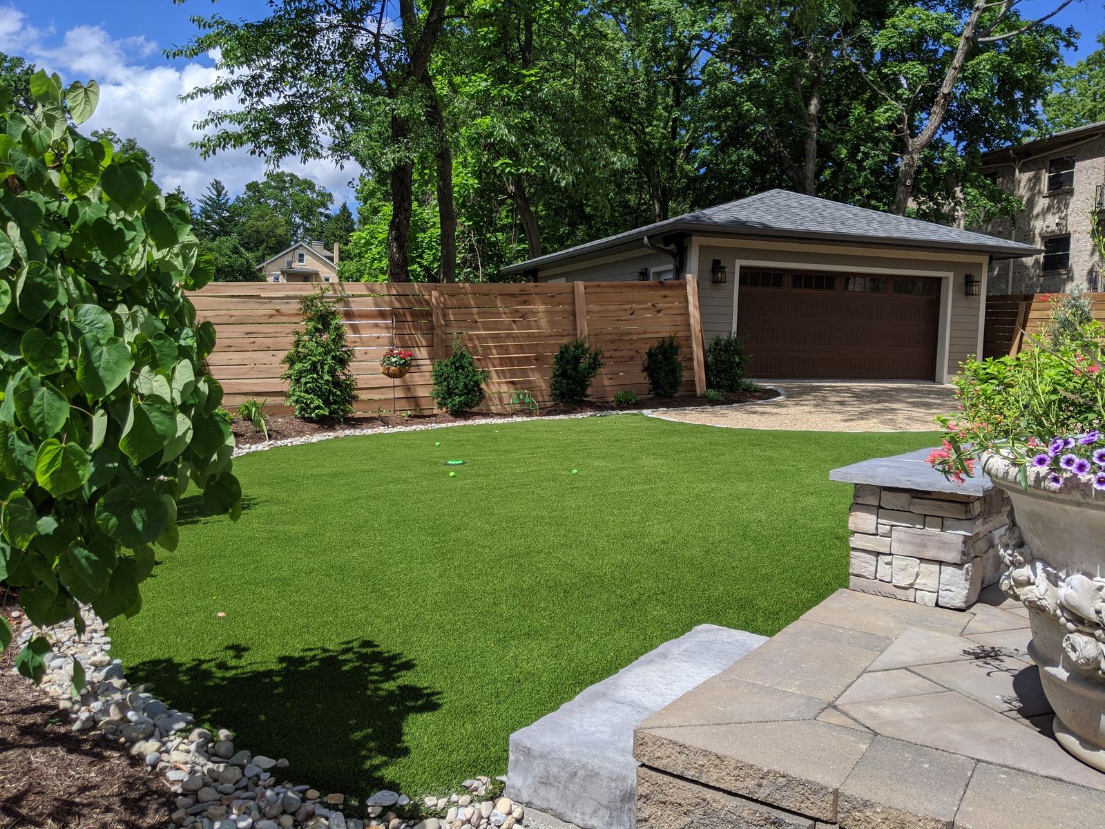 Backyard with artificial turf lawn, cedar privacy fence, and detached garage
