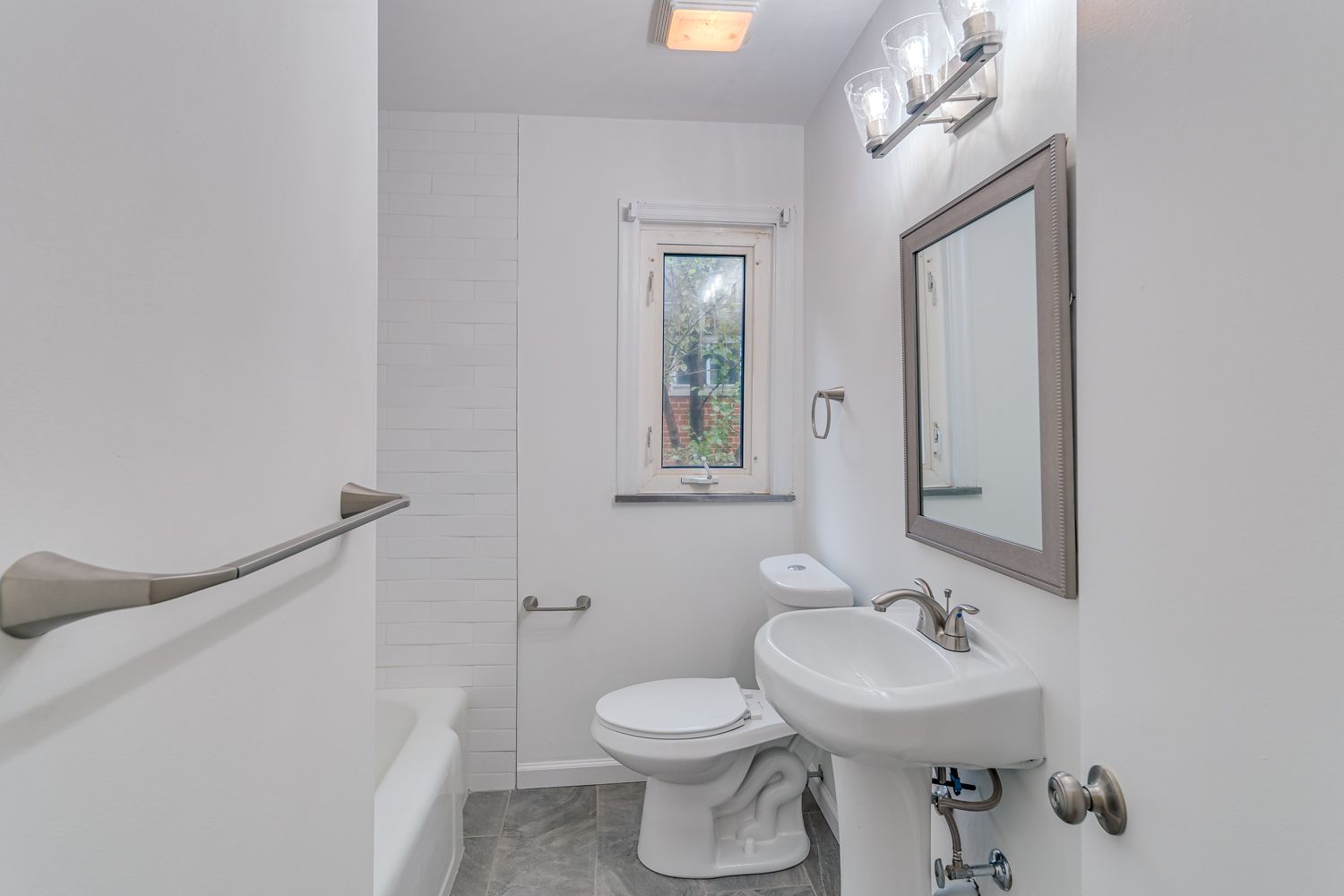 Updated hall bathroom with pedestal sink and bright white finishes
