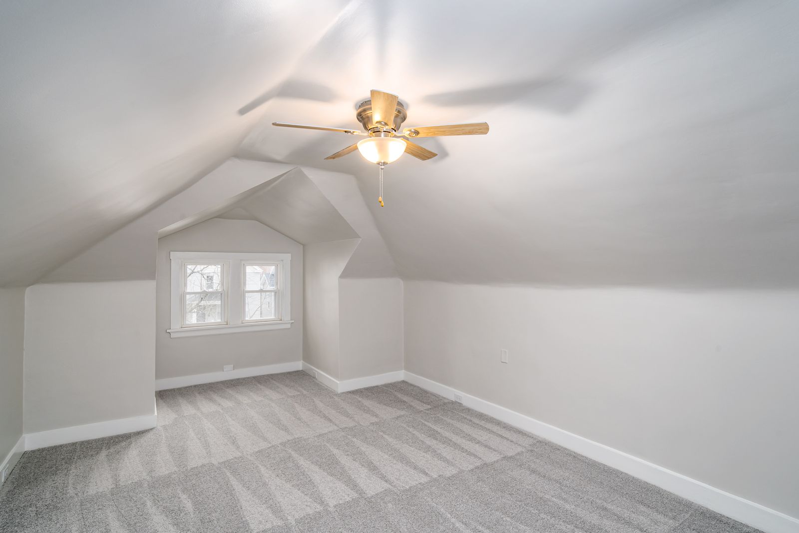 Finished attic bedroom with sloped ceilings, a dormer window alcove, new carpet, and a ceiling fan