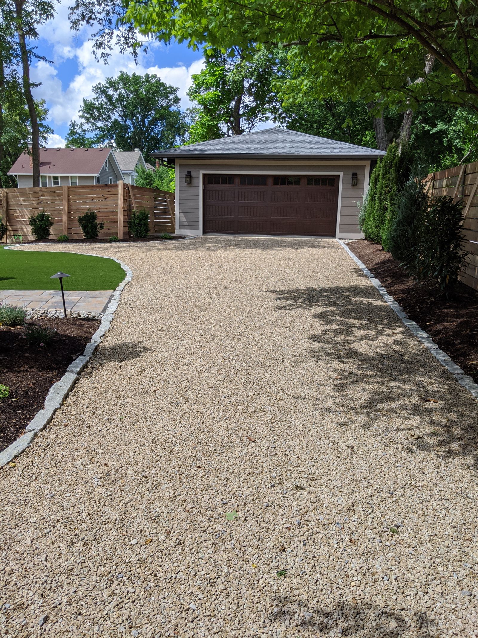 Decorative gravel drive leading to a custom detached garage