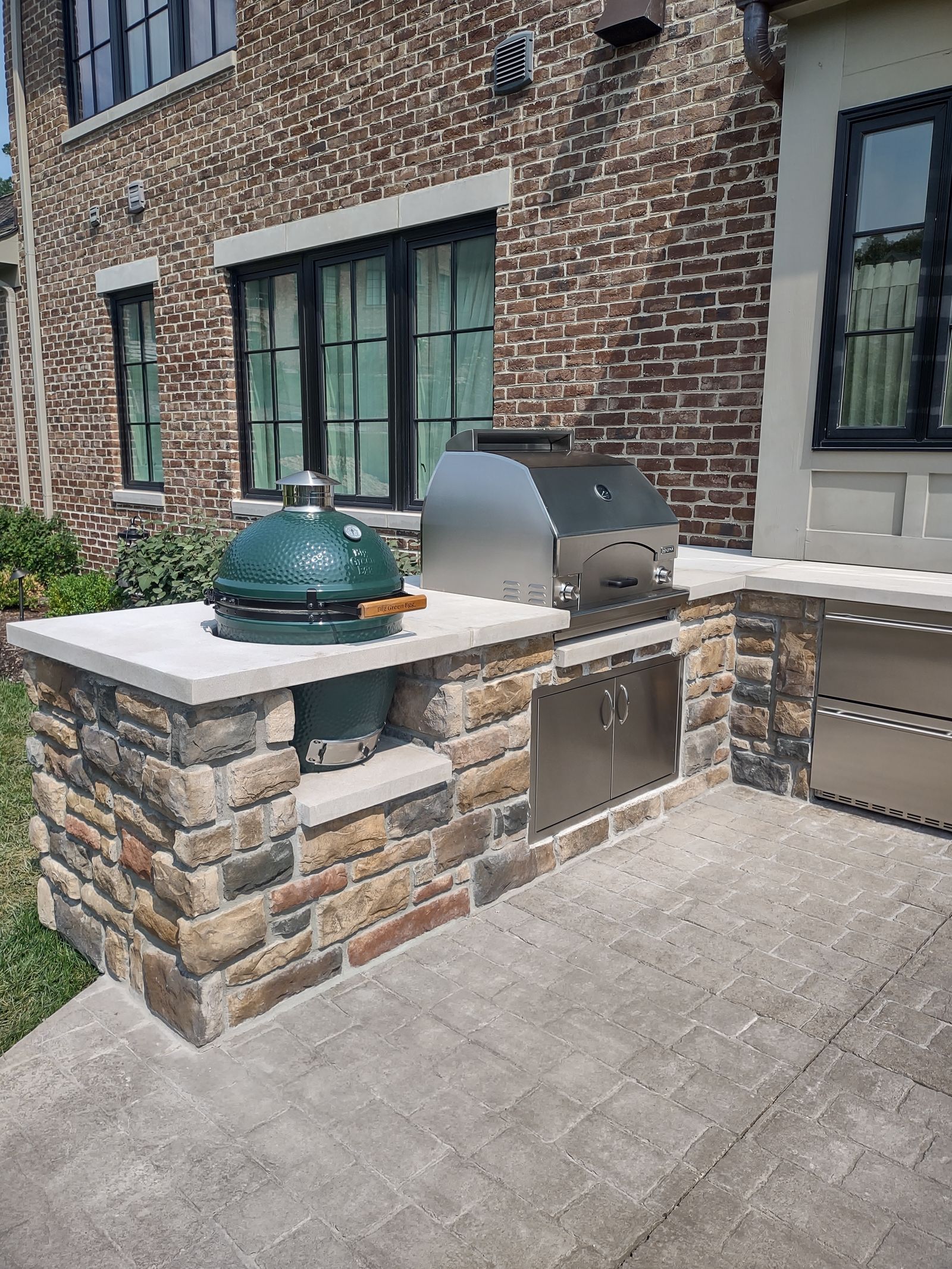 Built-in ceramic grill station with stone veneer on a paver patio