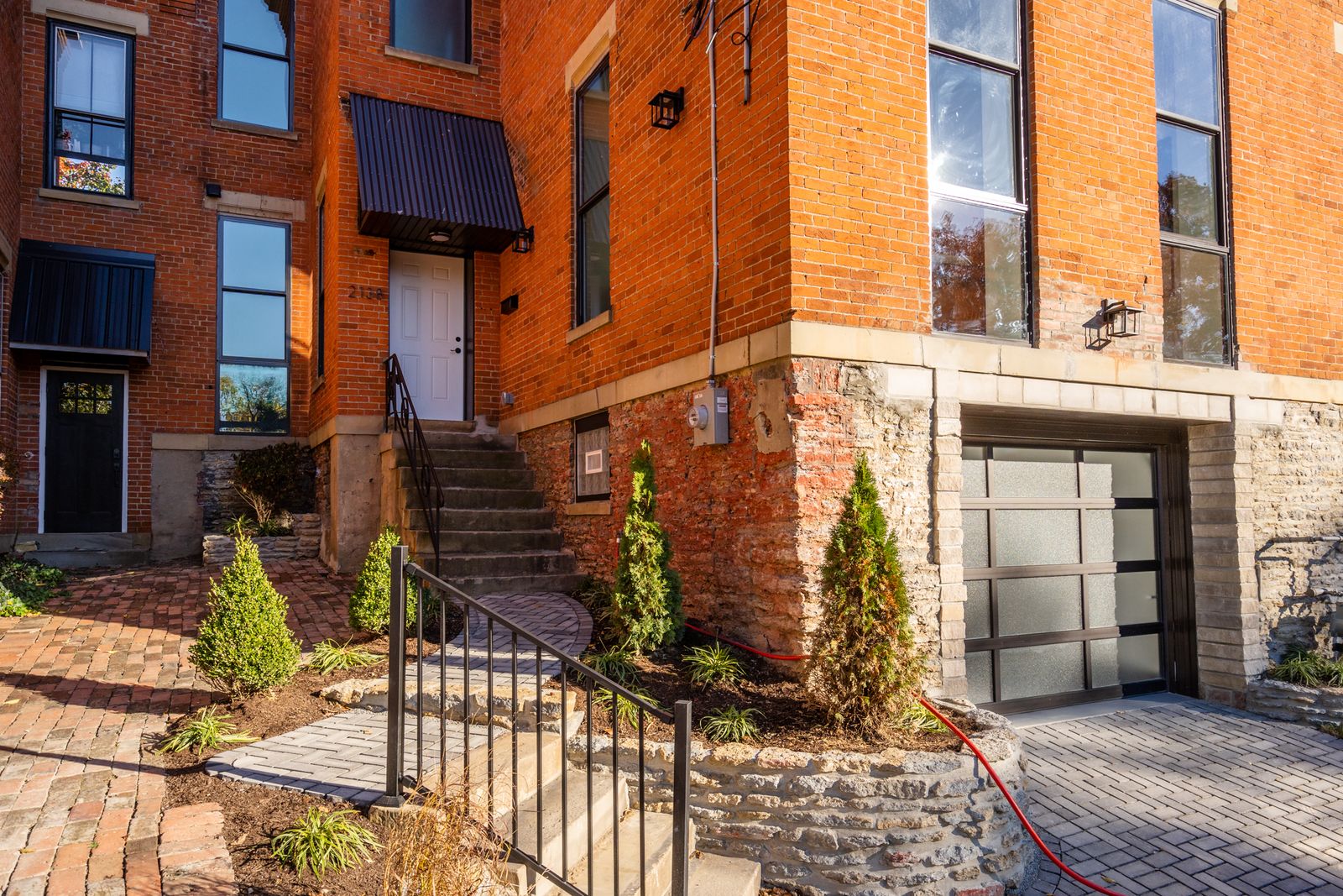 Renovated rear courtyard with paver patio, entry stairs, and glass-panel garage door
