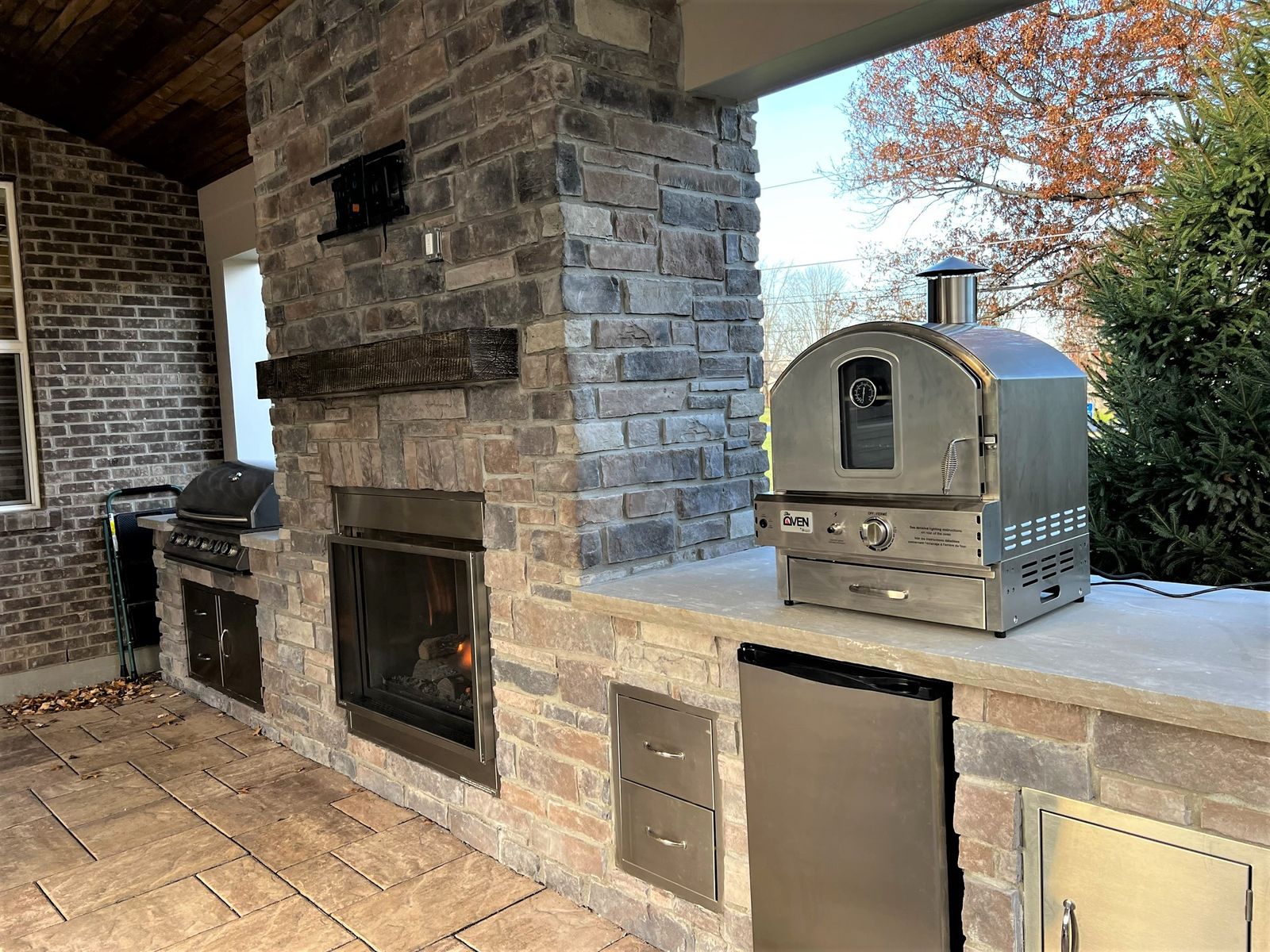 Covered outdoor kitchen with stone counters and stainless appliances