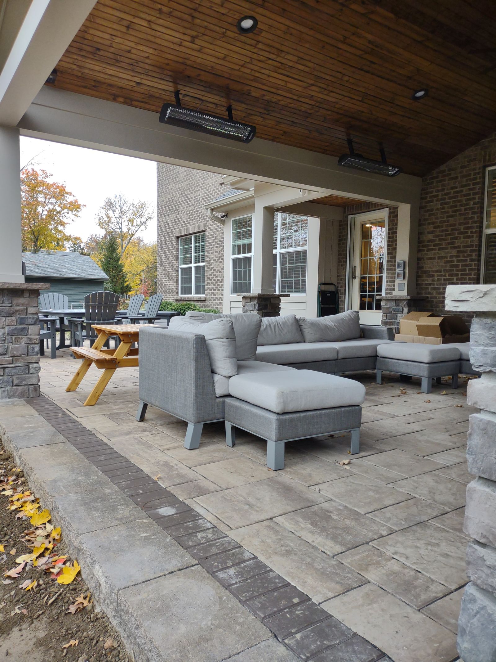 Covered outdoor living room with sectional seating and stained wood ceiling