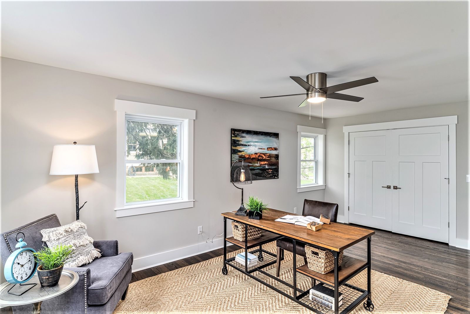 Home office with wood-top desk, ceiling fan, and double closet doors