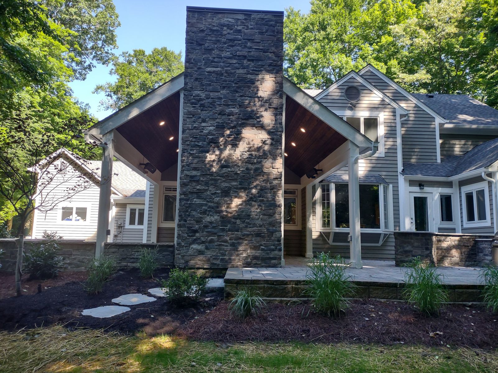 Covered porch with a full-height stone chimney fireplace