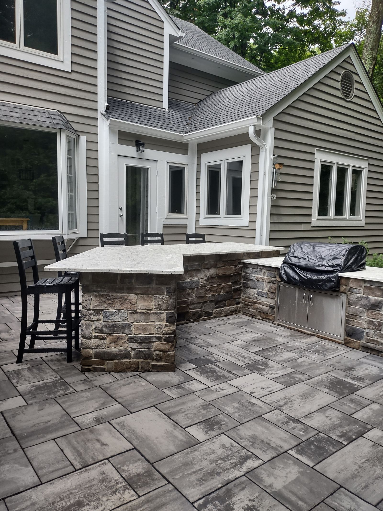 Outdoor kitchen bar with stone veneer counter and stool seating