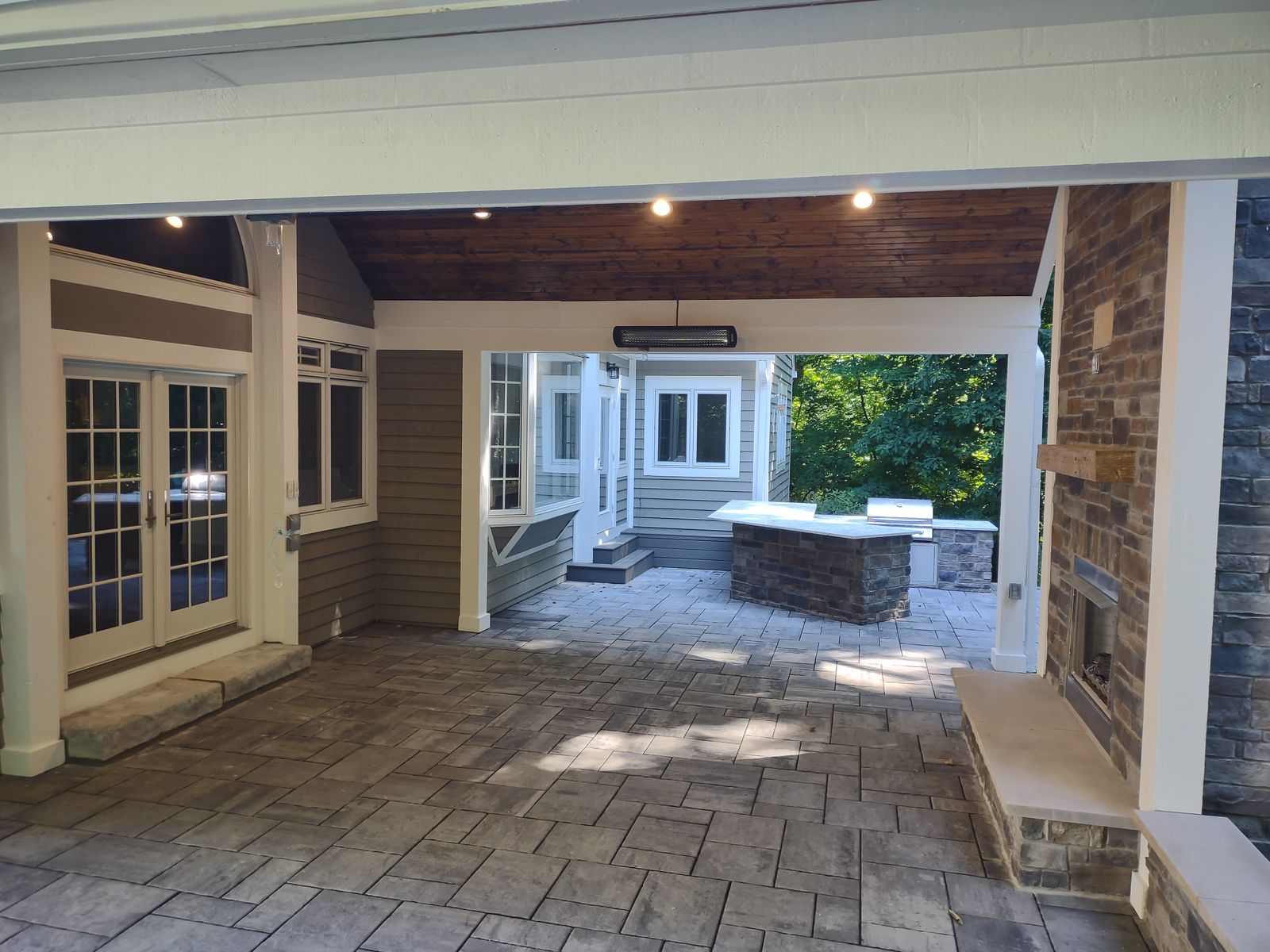 Spacious covered porch interior with wood ceiling and paver floor