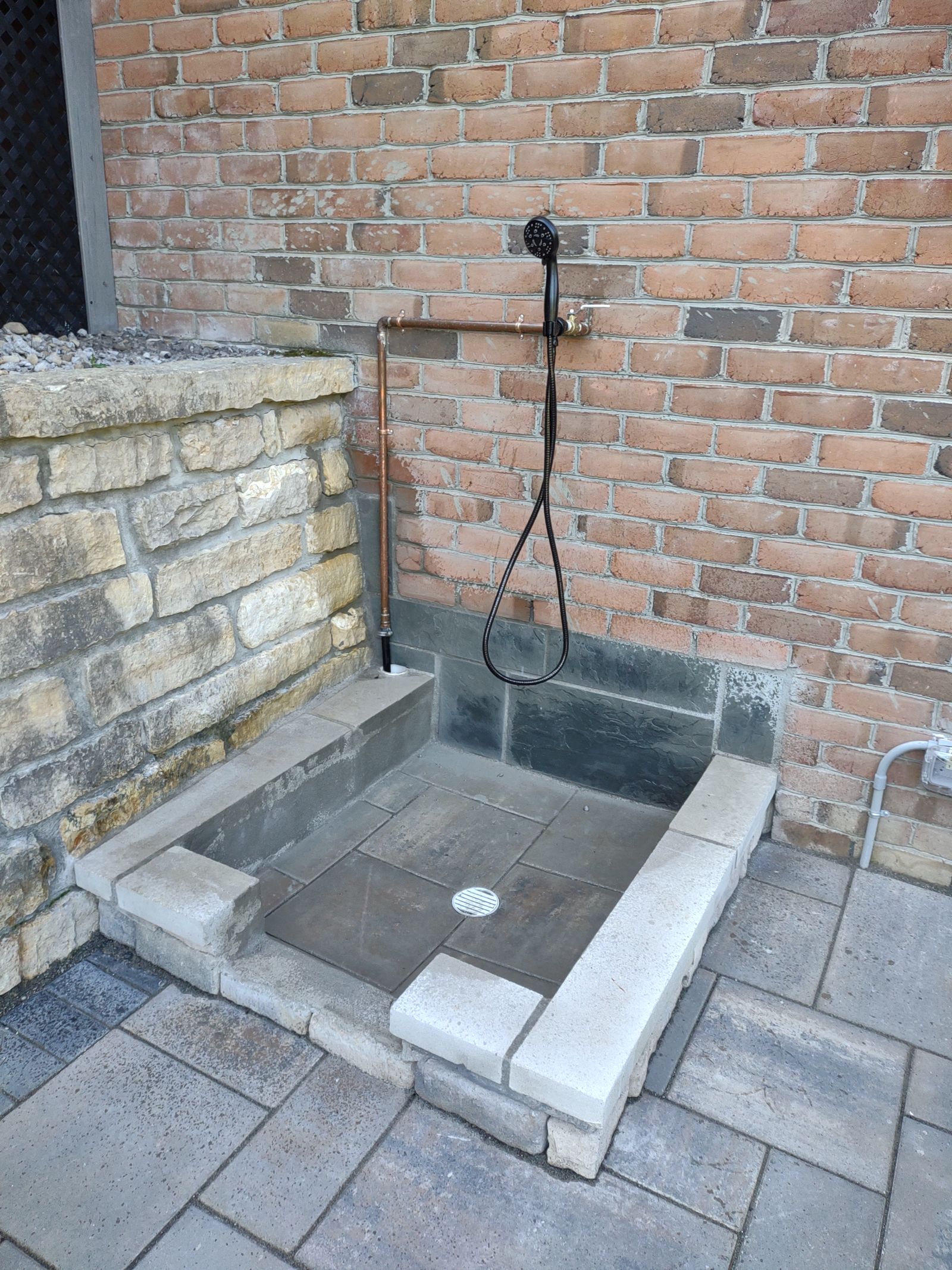 Outdoor shower with copper fixtures and stone bench seating