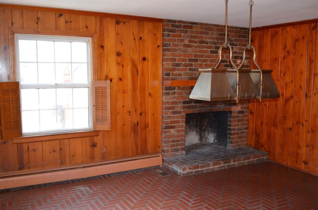 Original wood-paneled family room with brick fireplace before renovation