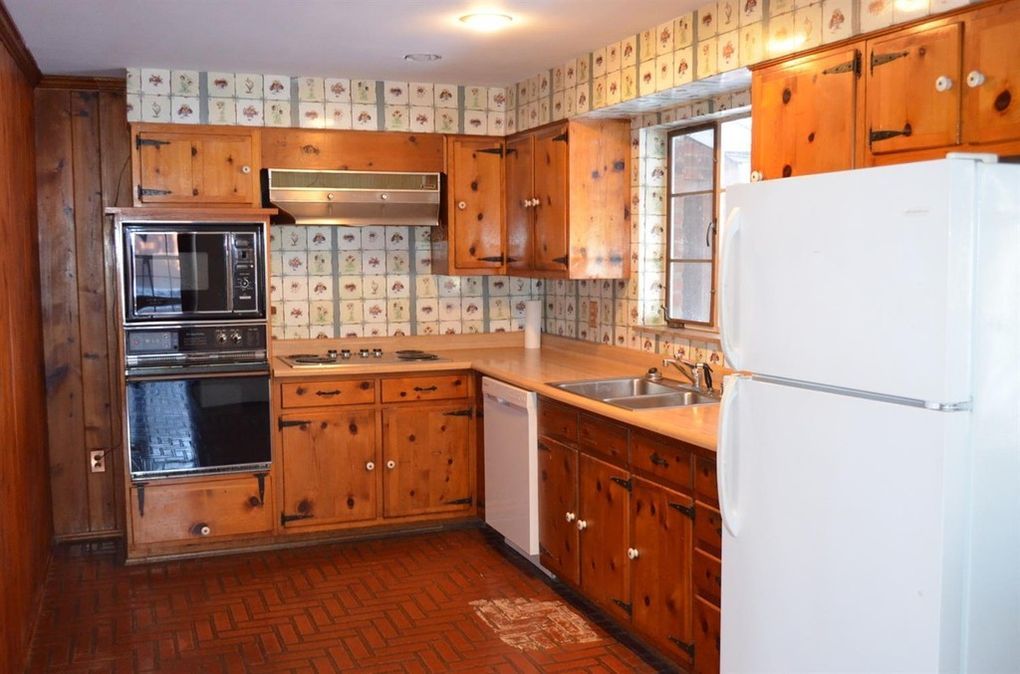 Original kitchen with wood cabinets and brick flooring before renovation
