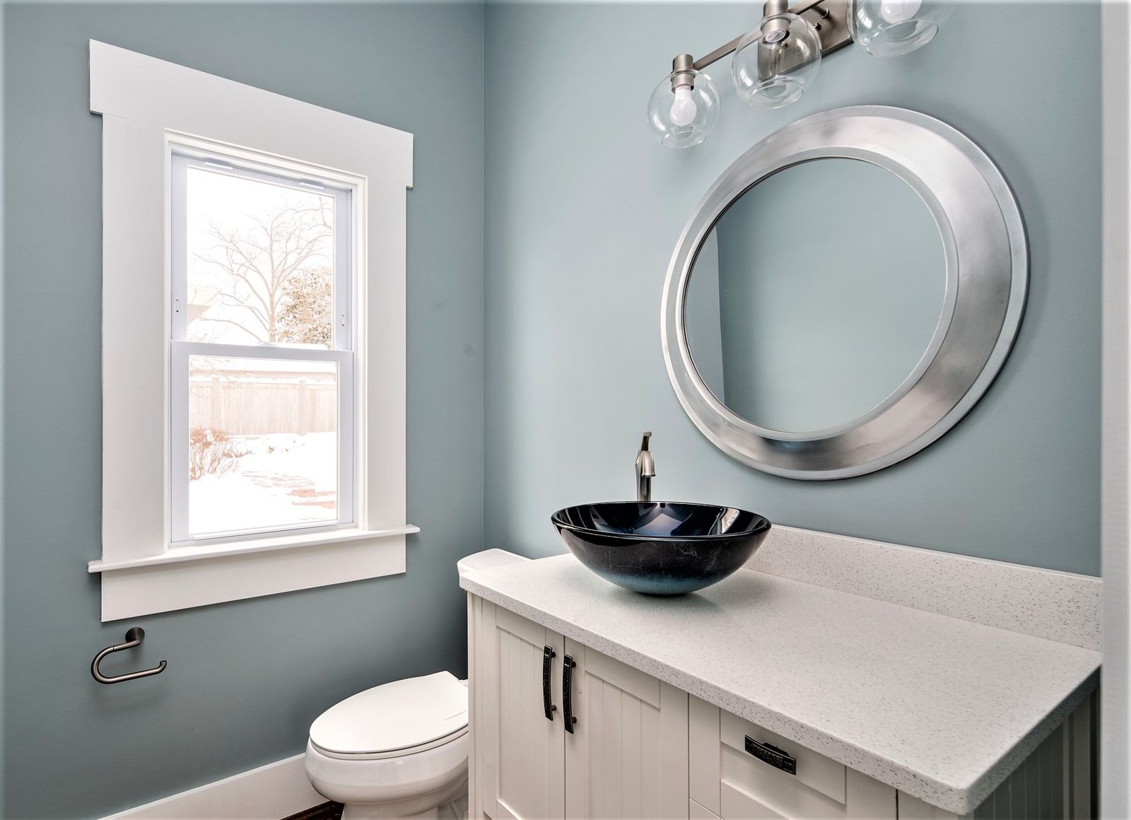 Updated powder room with dark vessel sink and round mirror